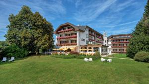 ein Hotel mit Stühlen auf dem Rasen davor in der Unterkunft Hotel Schönruh in Drobollach am Faakersee