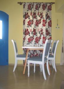 einen Esstisch mit 4 Stühlen und einem Vorhang in der Unterkunft Corina Apartments , Corina 2-studios in Sitia