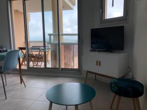 a living room with a television and a table and chairs at LES CEDRES, Résidence LES OCEANES in Pornichet