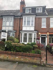 uma casa de tijolos vermelhos com janelas brancas e arbustos em Carlton Guest House em Stratford-upon-Avon