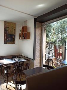 a restaurant with tables and chairs and a large window at Hotel de la Place in Loyettes