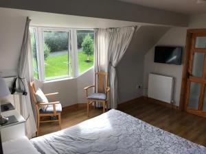 a bedroom with a bed and two chairs and a window at Grove Lodge B&B in Monaghan