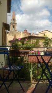 een balkon met een tafel en stoelen en een klokkentoren bij Casa Traquandi in Castiglion Fiorentino
