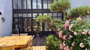 a patio with a wooden table and some pink flowers at La Martinoise Patio in Saint-Martin-de-Ré