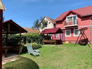 a yard with a chair and a table and a house at Casa Zmeilor in Tăşnad