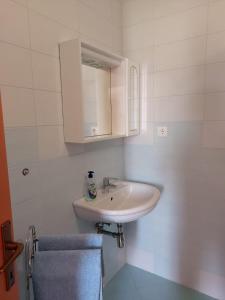 uma casa de banho branca com um lavatório e um espelho em Apartmani Anita em Malinska
