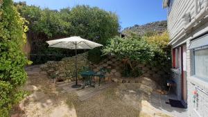 Glencairn的住宿－Self catering Holiday Apartment，一个带桌子和遮阳伞的庭院