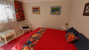 a bedroom with a red bed and a chair at Self catering Holiday Apartment in Glencairn