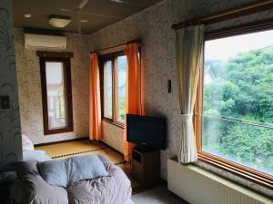 um quarto com duas camas e uma televisão e janelas em Hotel Radish House ホテルラディッシュハウス em Senboku