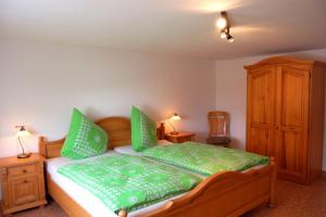 a bedroom with a wooden bed with green pillows at Ferienhaus - Vakantiehuis, Ferienwohnung, 100 qm, Rollmann, 54578 Nohn, Eifel- Nürburgring in Nohn
