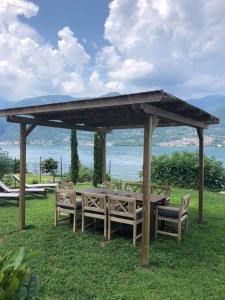 een houten picknicktafel en stoelen onder een paviljoen bij Como Lake view House in Lezzeno