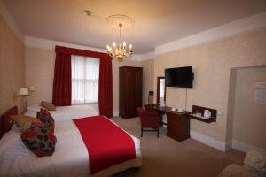 a hotel room with a bed and a desk and a television at Gipsy Hill Hotel in Exeter