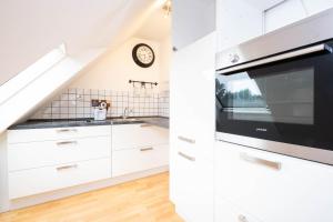 a kitchen with white cabinets and a sink and a microwave at Schönebeck Apartment in Essen