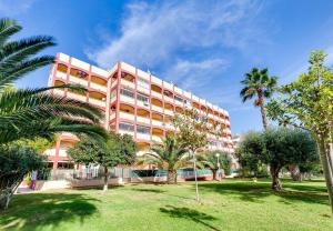 a pink building with palm trees in front of it at Appartement Torre La Mata in Torrevieja