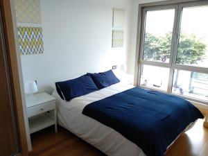 Schlafzimmer mit einem Bett mit blauer Bettwäsche und einem Fenster in der Unterkunft Apto. Vista Playa Poniente in Gijón