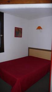 a bedroom with a red bed with a red comforter at LES MENUIRES REBERTY in Les Menuires