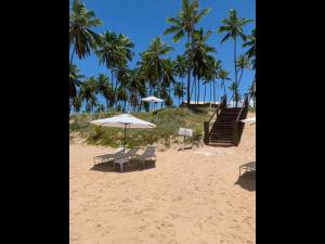 a beach with two chairs and an umbrella and stairs at Apt Coral Azul Iberostate Praia do Forte in Praia do Forte