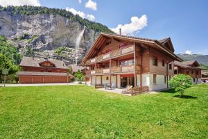 a large wooden house with a mountain in the background at Apartment Trümmelbach, Comfortabl & Cozy, Private Terrace with best views in Lauterbrunnen