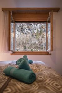 a window in a bedroom with a green pillow on a bed at Apartment Trümmelbach, Comfortabl & Cozy, Private Terrace with best views in Lauterbrunnen