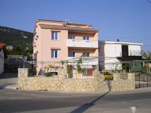 a building with a stone fence in front of it at Apartmani Roko in Baška