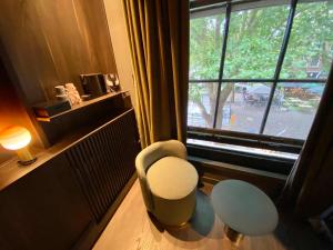 a room with a chair and a large window at Hotel Frank since 1666 in Amsterdam