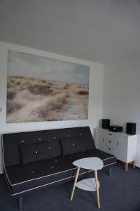a living room with a black couch and a painting at Maritim #1 in Peenemünde