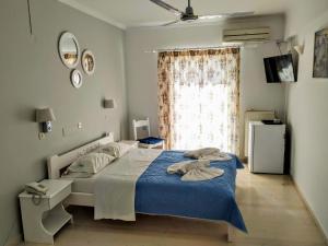 ein Schlafzimmer mit einem Bett mit blauer Bettwäsche und einem Fenster in der Unterkunft Avra Beach Hotel in Nydri