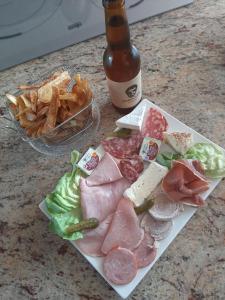 un plato de carne y queso y una botella de cerveza en La Chevrie, en Les Oubeaux