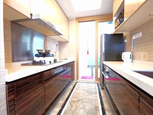 een keuken met houten kasten en een zwarte koelkast bij R&F Princess Cove by Maco Home in Johor Bahru