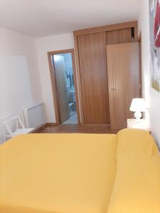 a bedroom with a yellow bed and a closet at Apartamento Barbanza con plaza de garaje in Porto do Son
