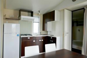 a kitchen with brown cabinets and a white refrigerator at Camping Albergue Tau in San José
