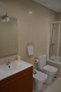 ein Badezimmer mit einem Waschbecken, einem WC und einem Spiegel in der Unterkunft Cerca da Vitória 1 Sesimbra in Sesimbra