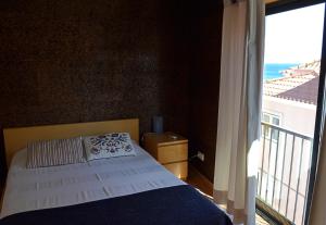 ein Schlafzimmer mit einem Bett und einem großen Fenster in der Unterkunft Cerca da Vitória 1 Sesimbra in Sesimbra