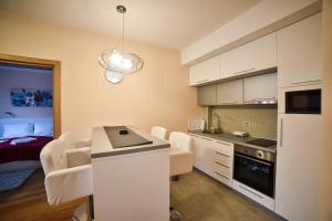 eine Küche mit weißen Schränken und ein Wohnzimmer in der Unterkunft Apartman Pavle in Zlatibor