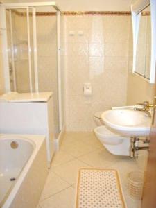 a bathroom with a tub and a sink and a toilet at Chalet Decrestina in Campitello di Fassa