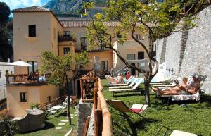 a group of people sitting on lounge chairs in a courtyard at Cartiera Apartment with Pool by AMALFIVACATION in Amalfi