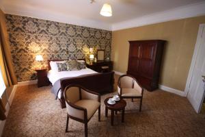 a room with a bed, chair, table and a lamp at Gipsy Hill Hotel in Exeter