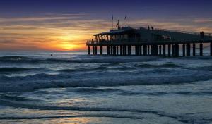 um cais no oceano com ondas e o pôr do sol em Attico panoramico fronte mare em Lido di Camaiore