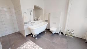 a white bathroom with a tub and a toilet at Big 4 BR Flat with Bathtub by CPH City Hall Square in Copenhagen