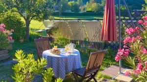 une table et deux chaises avec une table et un parasol dans l'établissement Une envie de montagne, à Guillestre