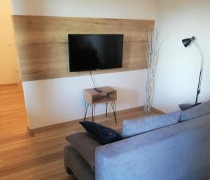 a living room with a blue couch and a flat screen tv at Apartment Leggero in Moravske-Toplice