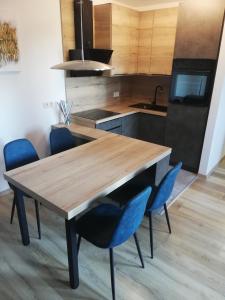 eine Küche mit einem Holztisch und blauen Stühlen in der Unterkunft Apartment Leggero in Moravske-Toplice