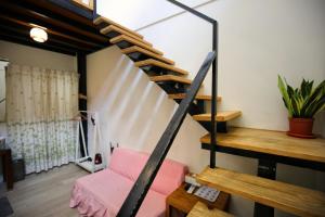 a spiral staircase in a room with a pink couch at Windhouse B&B in Tainan