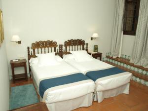 a bedroom with two beds with white and blue sheets at Parador de Alcañiz in Alcañiz