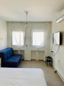 a living room with a blue couch and two windows at Royal Sea Studio in Netanya
