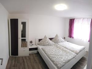 ein weißes Schlafzimmer mit einem Bett und einem Fenster in der Unterkunft Haus Waldidyll in Lauta
