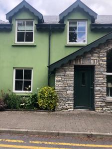 a green house with a green door and windows at Cromwells Court in Kenmare