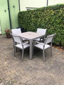 une table blanche et quatre chaises assises à côté d'une haie dans l'établissement Cromwells Court, à Kenmare