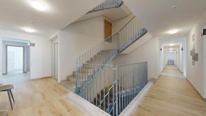una escalera en una casa con paredes blancas y suelo de madera en Nonanteneuf Appart-hôtel - Aigle, en Aigle