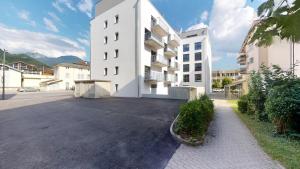 un parcheggio vuoto di fronte a un edificio bianco di Nonanteneuf appart hōtel Aigle - contactless check-in ad Aigle